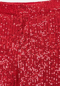 Tissu rouge densément couvert de petites paillettes brillantes créant une surface scintillante et réfléchissante.