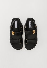 Black leather sandals featuring two wide straps, gold hardware accents, and a smooth finish. Buckle detail on the upper strap adds distinction.