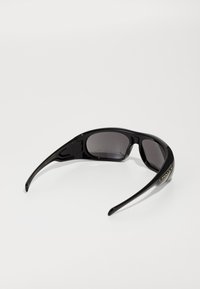 Óculos de sol pretos com um design elegante e envolvente. Apresentam lentes cinza-escuro, armações contornadas e detalhes em logo dourado nas hastes.