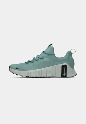 Zöldeskék és szürke sportcipő fekete Nike swoosh logókkal, hátsó húzófüllel és texturált talppal, amelyet futásra vagy edzésre terveztek.