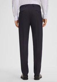 Marineblauwe broek met een slim fit, gemaakt van gladde stof. Bevat dubbele achterzakken en riemlussen, in combinatie met gepolijste zwarte schoenen.