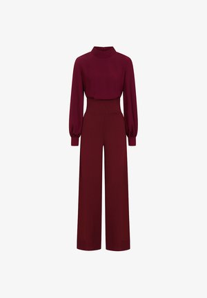 Mono burdeos de manga larga con cuello alto, mangas abullonadas, cintura ajustada y pantalones de pierna ancha sobre un fondo blanco.