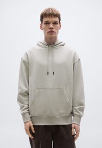 Helehall hall kapuutsiga dressipluus, millel on eesmine tasku ja soonikkoes mansetid. Rinnal on logo ning lõdva lõikega disain.