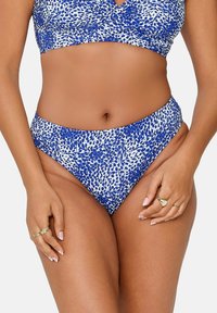 Niebieski i biały bikini z fakturowanym, kropeczkowym wzorem; z zawijasowym topem i spodniami o wysokim stanie, gładkim materiałem i minimalną ilością dodatków.