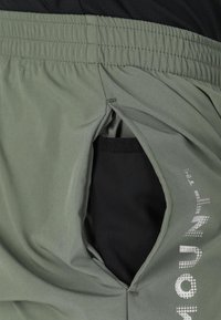 Shorts sportivi verde chiaro con una cintura elastica strutturata e un'apertura per tasca in rete sul lato, con un logo stampato in bianco.