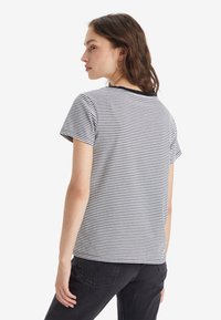 Randig bomullst-shirt med kort ärm, svart och vita horisontella ränder, rund halsringning, avslappnad passform, minimalistisk design, enkel baksida.