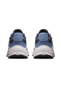 Scarpe sportive in camoscio blu e rete con suola imbottita bianca. Presentano un tacco arrotondato e un logo sul retro.