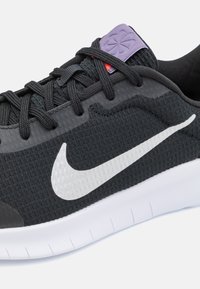 Crne atletske tenisice s teksturiranim mrežastim gornjim dijelom, bijelim Swoosh logom i jastučićem na jeziku s ljubičastim naglaskom. Bijela sredina s uzorcima.