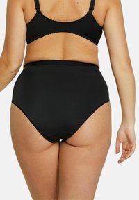 Culotte noire taille haute avec une texture lisse, un waistband festonné et un design sans coutures pour un ajustement épuré.