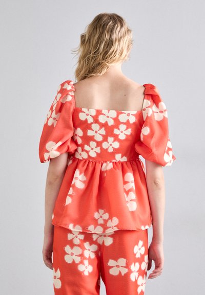 Korall peplum topp med puffet ermer og firkantet utringning, med hvite blomster mønstre. Lett stoff med en myk tekstur.