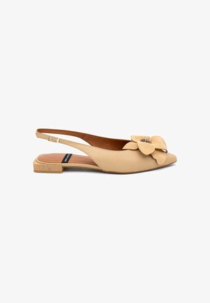 Scarpa flat beige con cinturino sul tallone, punta appuntita e grande decorazione floreale sulla parte anteriore, tacco basso in legno e cinturino regolabile alla caviglia.