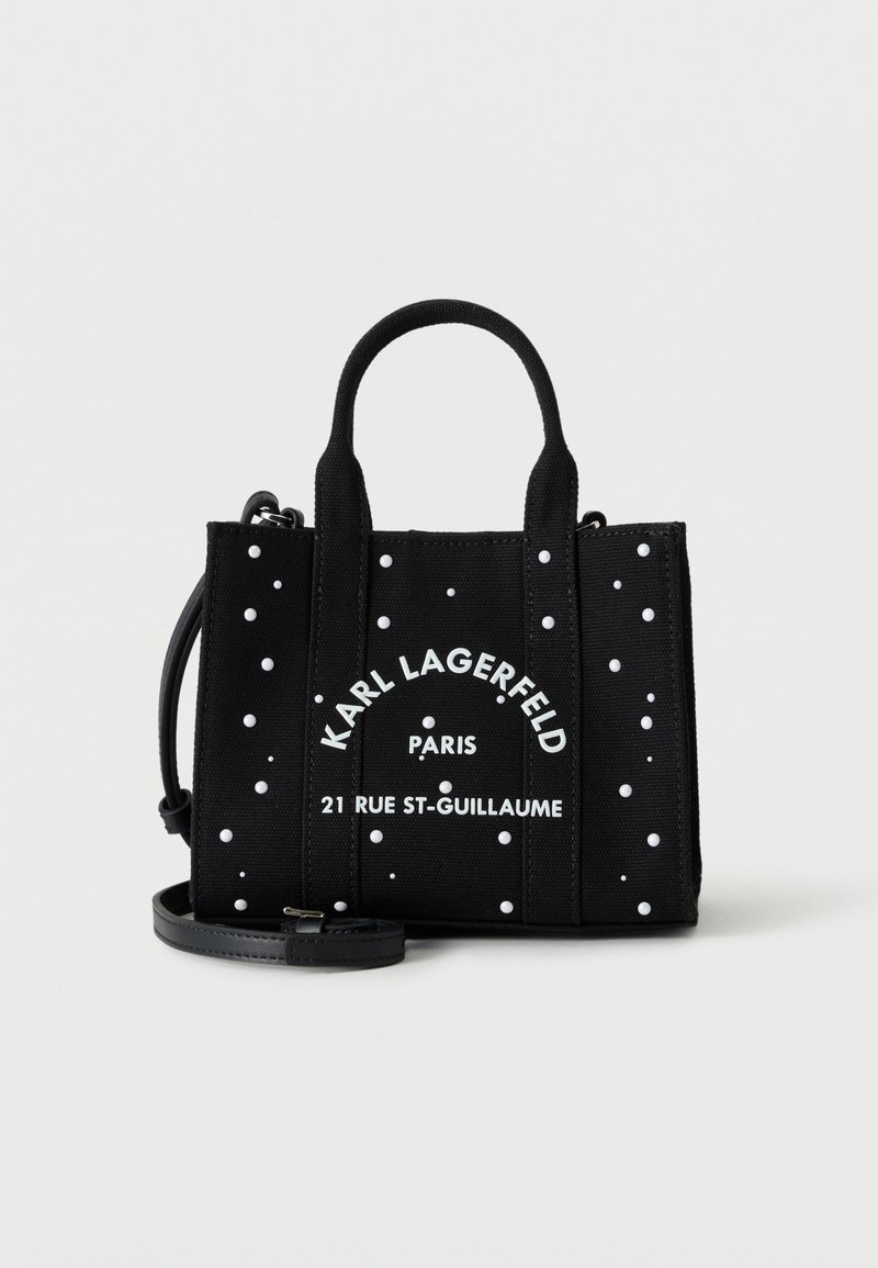 Μαύρη τσάντα tote Karl Lagerfeld με λευκές λεπτομέρειες με τρουκ, διπλές λαβές, αποσπώμενο ιμάντα ώμου και κείμενο "Paris 21 Rue St-Guillaume" στο μπροστινό μέρος.