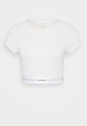 White cotton crop top with short sleeves, round neckline, and a contrast waistband featuring gray stripes and a logo. Soft texture.