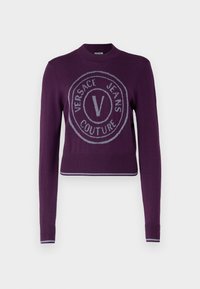 Pull en tricot violet à manches longues, avec un logo rond en argent, des poignets côtelés et un ourlet court.