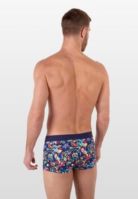 Bunte gemusterte Badehosen mit einem marineblauen Bund, die abstrakte Blumenmuster in leuchtenden Farben zeigen und aus dehnbarem Material gefertigt sind.