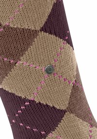 Ingrandimento di una calza con motivo a diamante nei colori beige, marrone e viola, con cuciture rosa e un'icona metallica con marchio.