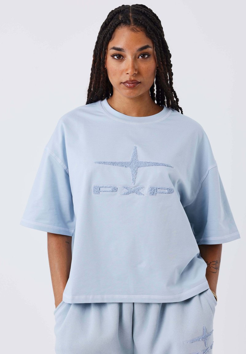 Lichtblauw oversized t-shirt met een zachte textuur, featuring een geborduurd "PXP" logo en een sterontwerp op de voorkant. Korte mouwen en een comfortabele pasvorm.