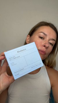 Kvinne som holder en eske med Biodance CERA-NOL Gel Toner Pads med fuktighetsgivende og hydrerende ingredienser, inkludert panthenol og hyaluronsyre.
