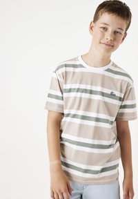 Camiseta de rayas marrón claro con rayas horizontales verdes y blancas, cuello redondo y pequeño logo en el lado izquierdo.