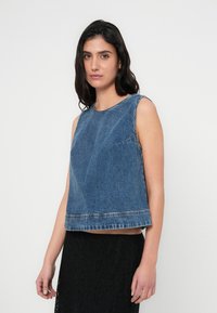 Αμάνικη μπλούζα από τζιν σε μεσαίο μπλε χρώμα, με ίσια γραμμή, ελαφρώς κομμένη και με διακριτική τελειότητα χωρίς ρίγα στο κάτω μέρος.