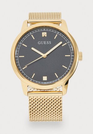 Montre bracelet en maille dorée avec un cadran noir, des index horaires dorés, des aiguilles simples et une petite fenêtre de date carrée à 3 heures.