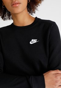 Svart sweatshirt i bomullsmix med rund halsringning. Har en liten vit Nike-logotyp broderad på bröstet. Slät textur.