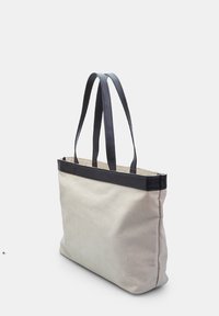 Beige Leinenshopper mit einem dunklen Lederbesatz und doppelten Tragriemen, der eine rechteckige Form und eine strukturierte Oberfläche aufweist.