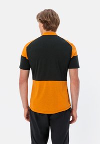 Chemise à manches courtes présentant des blocs de couleur noir et orange, fabriquée en tissu respirant avec un détail de fermeture éclair sur le côté. Design à coupe classique.