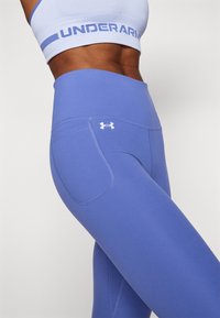 Lichtpaarse sportlegging met een hoge tailleband, voorzien van een zijzak en subtiele stikdetails. Gemaakt van rekbare stof.