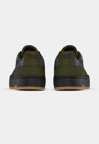 Sneakers in suede verde con suola in gomma nera. Presentano una punta arrotondata, colletto imbottito e pannelli laterali decorati.