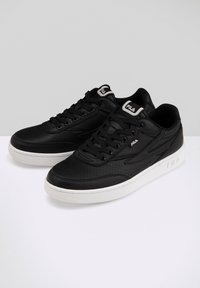 Sorte lædersneakers med perforeret design, hvid gummisål, snørebånd fortil og diskret branding på tungen og siden.