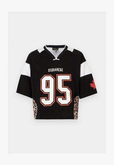 Μαύρη και λευκή κοντομάνικη φανέλα με το «DSQUARED2», τον αριθμό 95 με πορτοκαλί περίγραμμα, πλαϊνές πιέτες με λεοπάρ μοτίβο και κόκκινο φύλλο σφενδάμου στο μανίκι.