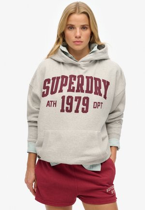 Grijze hoodie met "SUPERDRY ATH 1979 DPT" in bordeauxrood, met een kangoeroezak en een gestreept teal onderhemd, gecombineerd met bordeauxrood shorts.