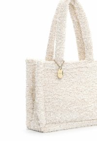 Borsa tote in tessuto testurizzato avorio, dotata di due manici spessi e un piccolo ciondolo dorato. Forma rettangolare semplice senza motivi visibili.