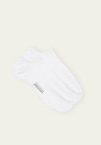 Weiße Knöchelsocken aus weichem Stoff, mit glatter Textur und einem kleinen grauen Logolabel an der Seite.