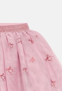 Růžová tylová sukně s třpytivým růžovým páskem, na kterém se rozprostírají malé vyšívané vzory červených mašliček.