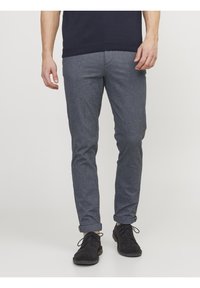 Grå mönstrade byxor i lätt material, med slim fit, uppvikta fållar och i kombination med svarta skor.