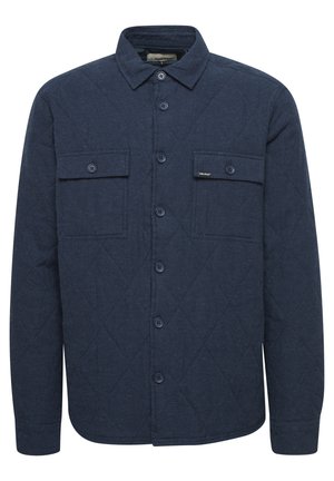 Marineblauwe gewatteerde shirtjas met een knoopsluiting aan de voorkant, twee borstzakken en een subtiel diagonale stiksels patroon. Gemaakt van textuurstof.