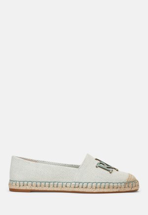 Alpargata plana tejida de color gris claro con suela de yute trenzado en beige y un emblema metálico decorativo en la parte superior.