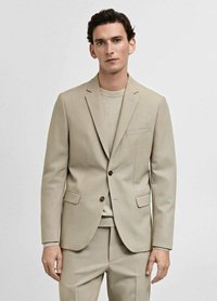 Beige kavaj med enkelknäppning, slagkrage och bruna knappar. Matchas med en ljusbeige tröja under.