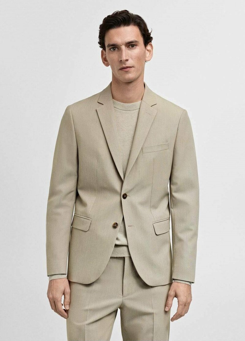 Beige kavaj med enkelknäppning, slagkrage och bruna knappar. Matchas med en ljusbeige tröja under.