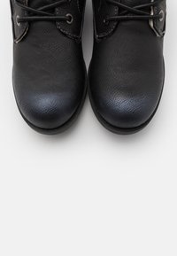 Czarne skórzane buty o textured wykończeniu, z zaokrąglonymi palcami i sznurowadłami, wyposażone w metalowe oczka i kontrastowe przeszycia wzdłuż szwów.