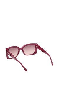 Gafas de sol burdeos con lentes degradadas, forma angular de ojo de gato y detalles texturizados en los laterales. Presentan un acabado brillante y varillas delgadas.