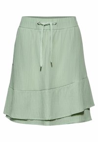 Svetle zelená sukně s texturovaným povrchem, stahovacími pásky v pase a vrstveným volánem na lemu. Geometrický vzor po celém povrchu.