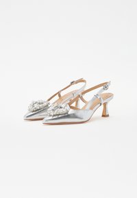 Tacones slingback metálicos plateados con punta afilada, que presentan un adorno ornamental de perlas y rhinestones en la parte delantera.