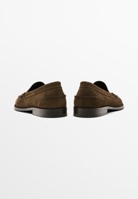 Brown suede loafers with a smooth exterior, flat sole, and stitching details along the upper. Classic slip-on design.