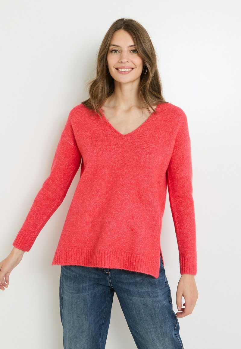 Jersey de cuello en V en un brillante color coral, hecho de un tejido texturizado. Mangas largas con puños acanalados y un corte holgado, con aberturas en los laterales.