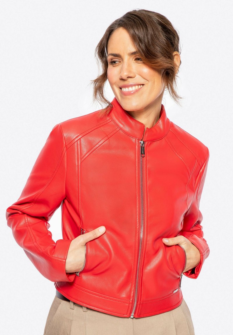 Veste en cuir rouge avec col montant, fermeture éclair à l'avant et poches latérales. Présente une texture lisse et un design ajusté. Longueur courte avec des coutures subtiles.