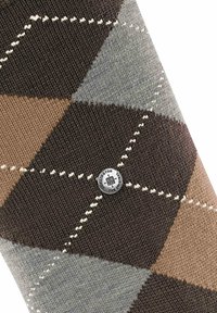 Calcetín de patrón argyle en marrón y gris, con tejido texturizado, que presenta un detalle de logotipo metálico redondo y costuras de acento blancas.