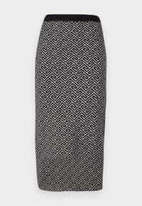 Jupe crayon en tricot avec des motifs noir et blanc, dotée d'une ceinture noire unie. Un design géométrique recouvre l'ensemble de la surface du tissu.